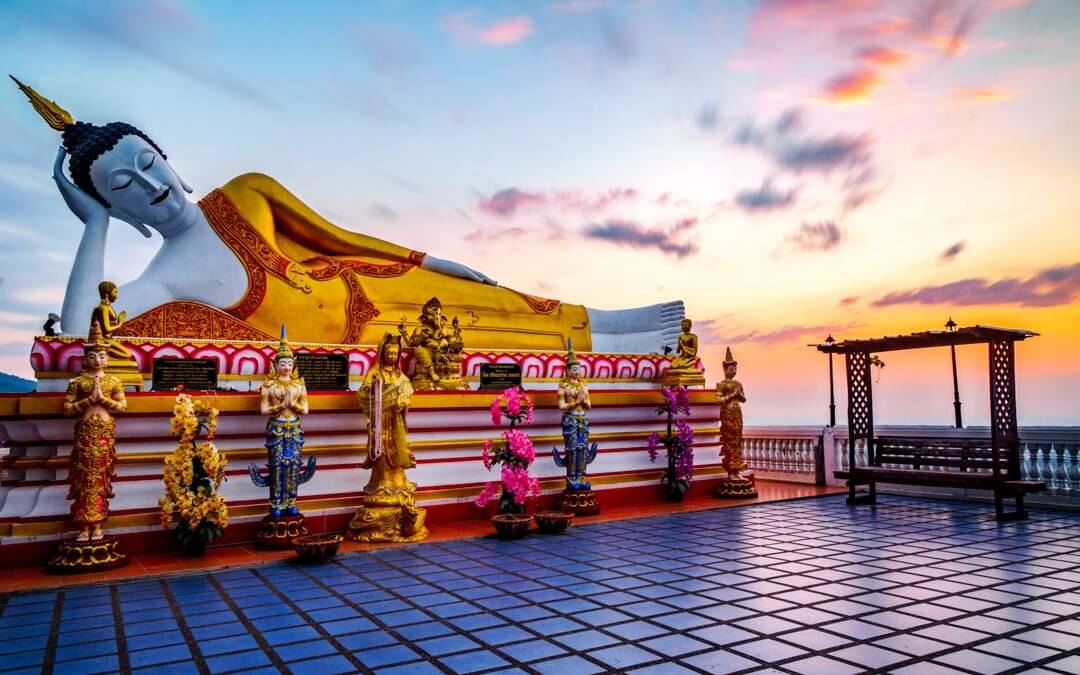 Liegende Buddhastatue mit Sonnenaufgang im Hintergrund